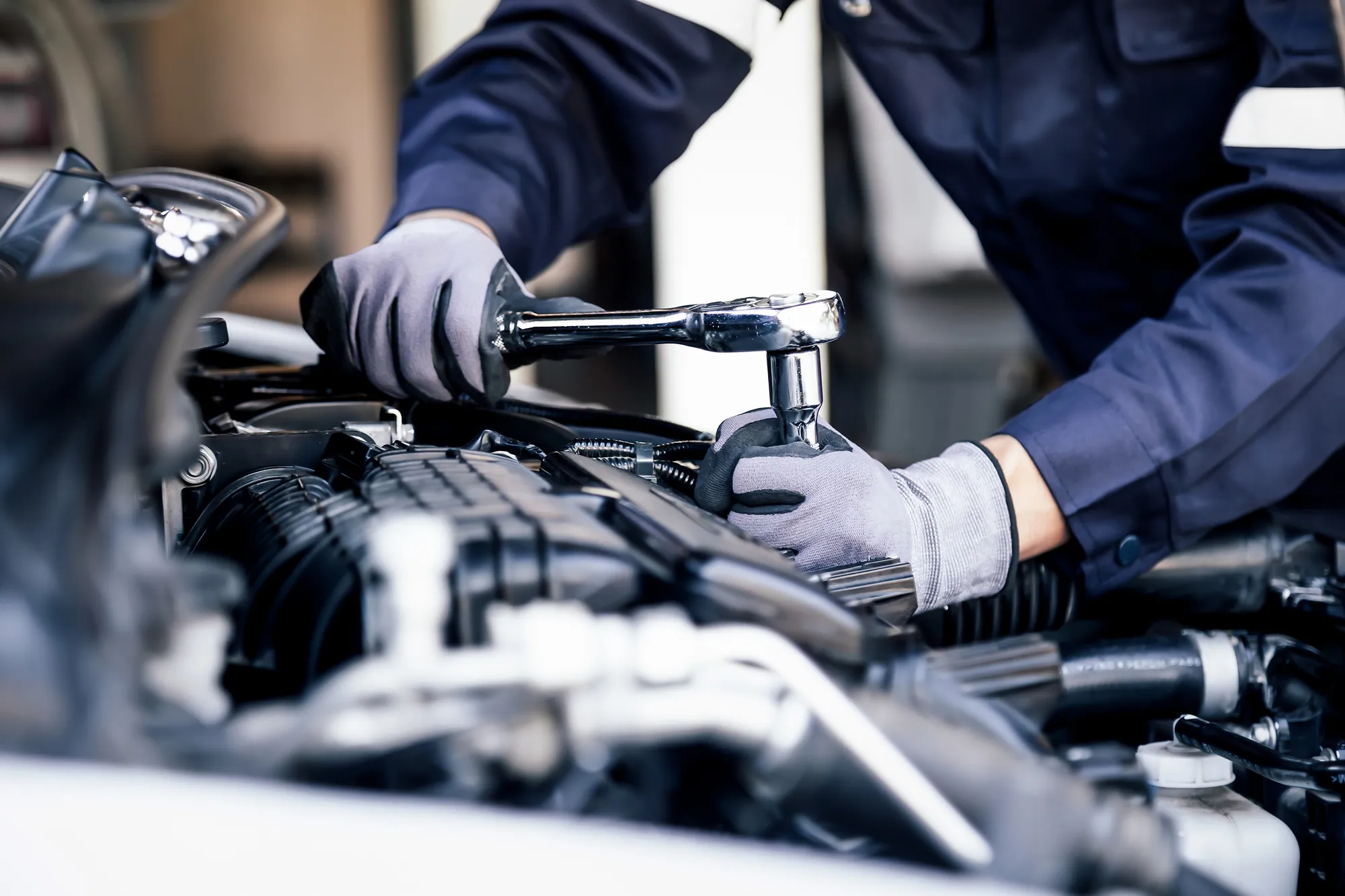 Mécanicien utilisant une clé à cliquet sur un moteur automobile.